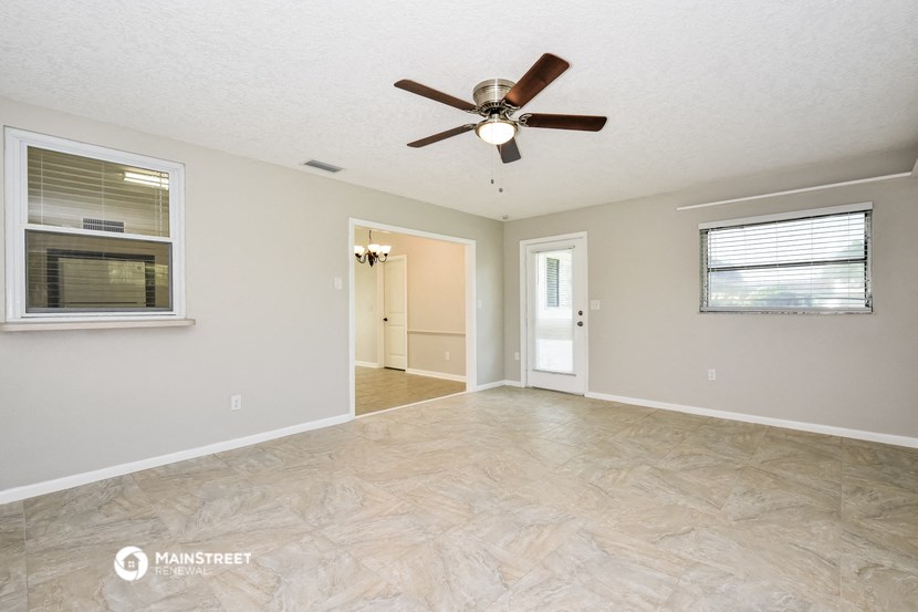the living room is spacious and has a ceiling fan
