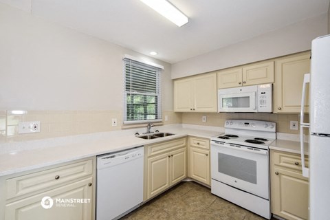 a kitchen with white appliances and white counters and cabinets