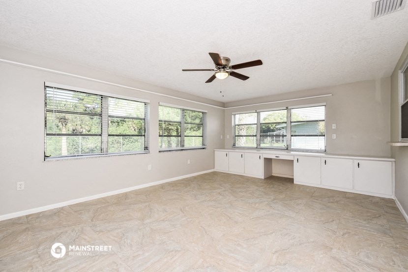 an empty living room with a ceiling fan and windows