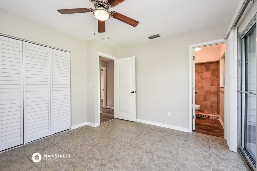 an empty living room with a ceiling fan and a closet