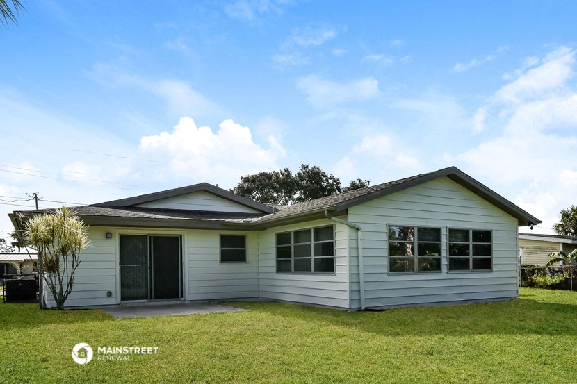 a small white house with a lawn and a blue sky