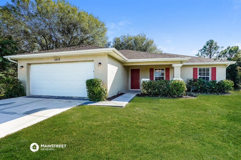 a white house with a garage door and a lawn