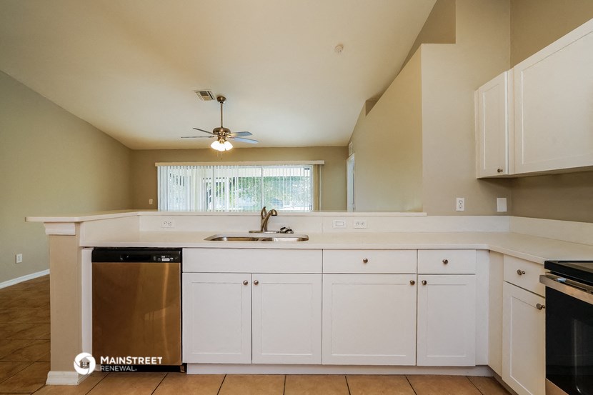 a kitchen with white cabinets and a dishwasher and a ceiling fan