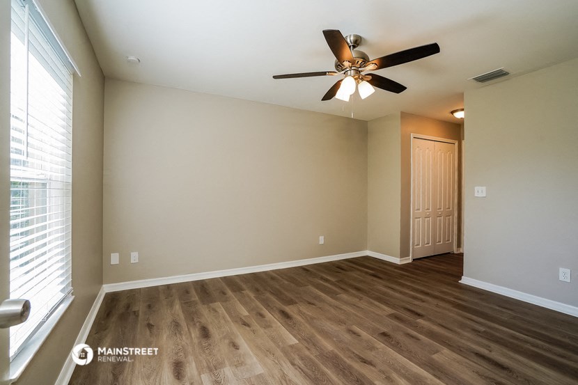 an empty living room with wood flooring and a ceiling fan