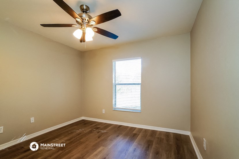 an empty room with a ceiling fan and a window