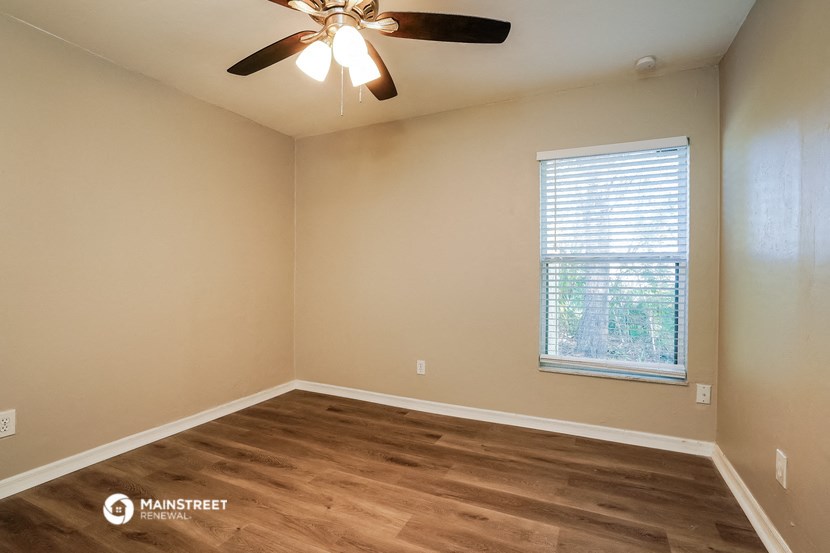 an empty room with a ceiling fan and a window