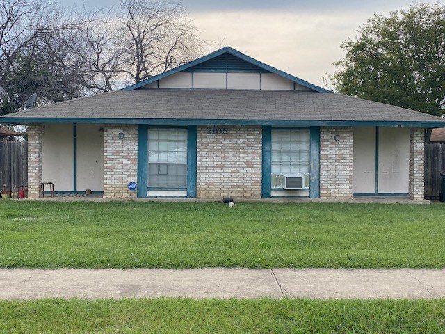 a small brick house with blue doors and a lawn