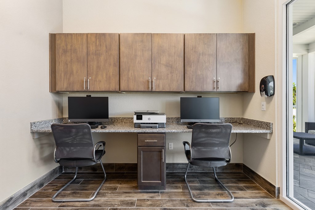 two desks with two monitors and two chairs in an office with two computers
