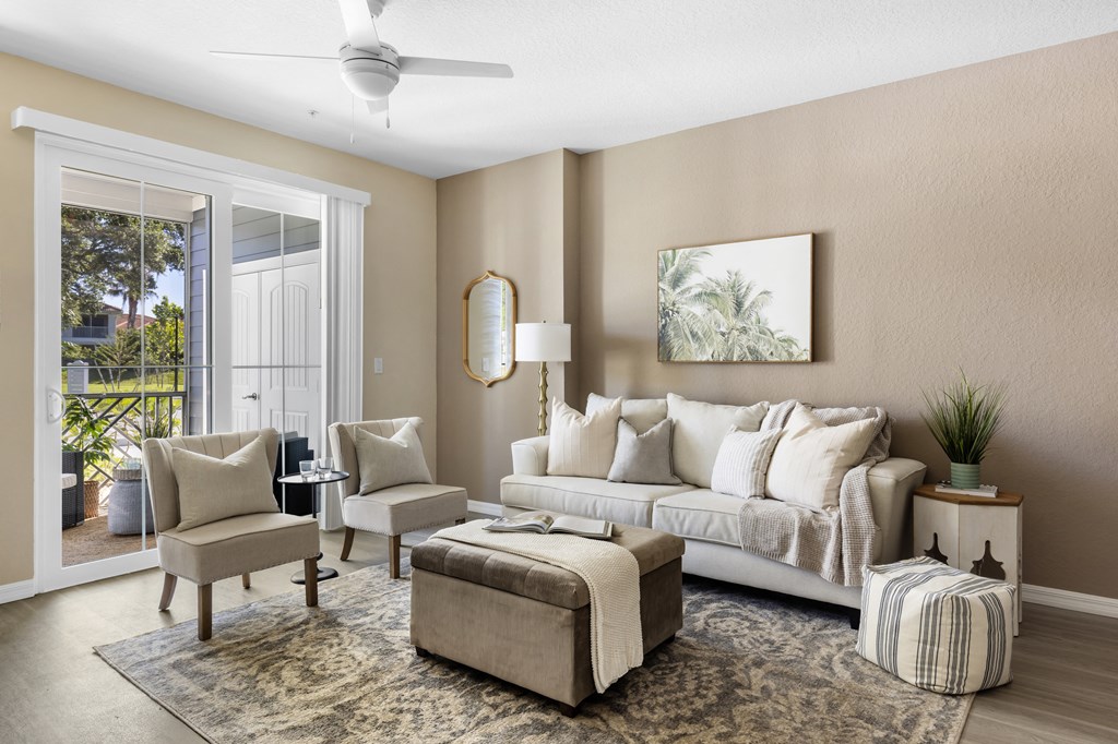a living room with a couch and chairs and a door to a balcony