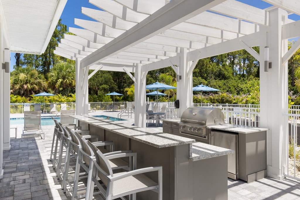 a patio with a grill and a bar with chairs