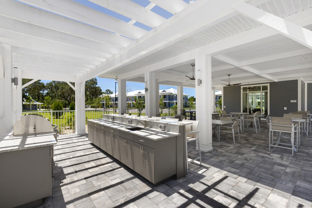 a patio with a grill and a white roof with tables and chairs