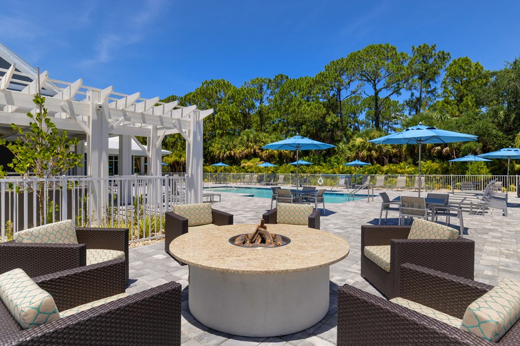 a patio with a fire pit and chairs and umbrellas