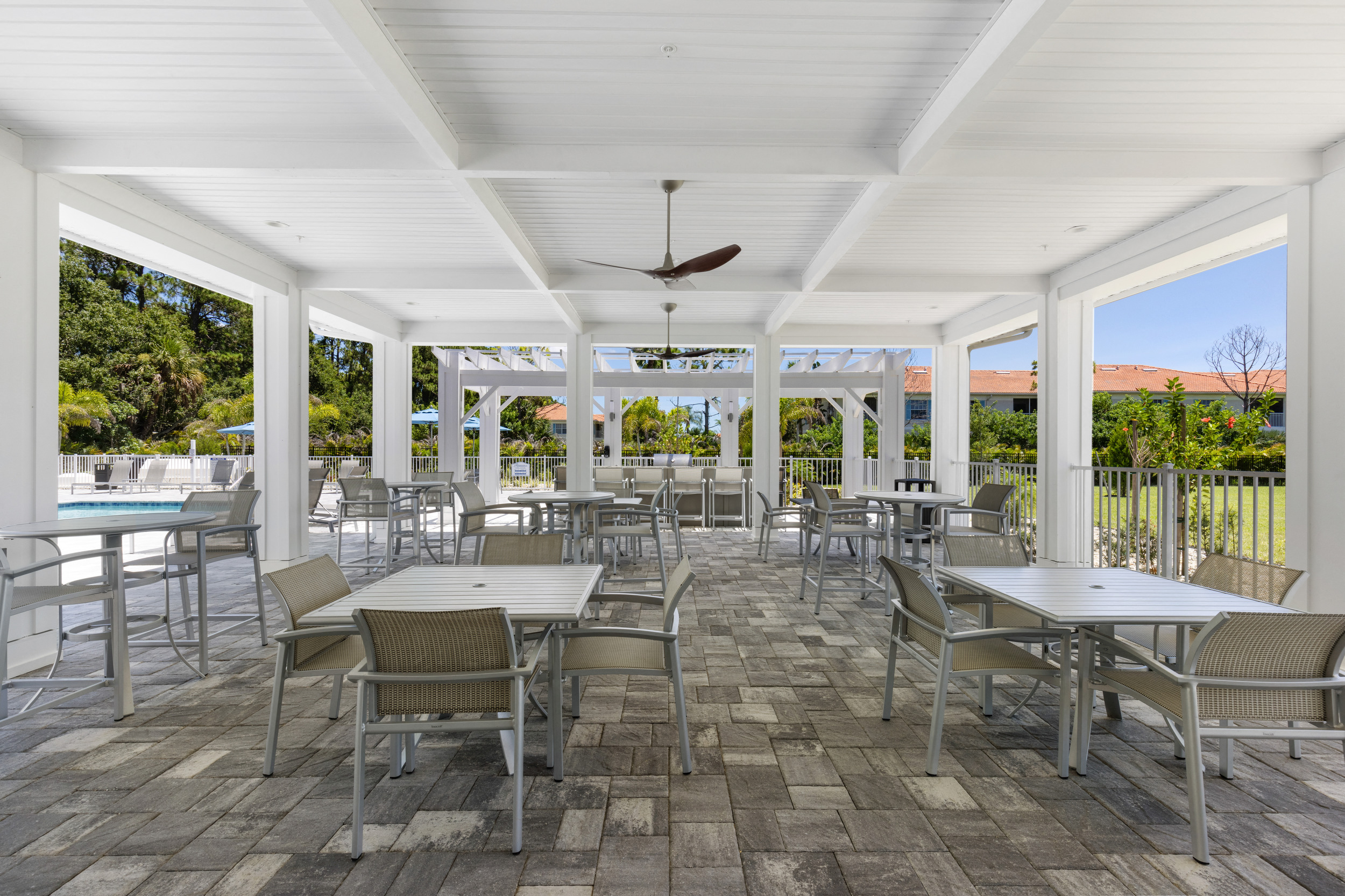 a covered patio with tables and chairs and a pool