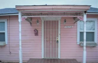 the front door of a pink house with a porch