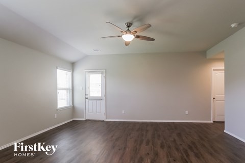 a living room with white walls and a ceiling fan
