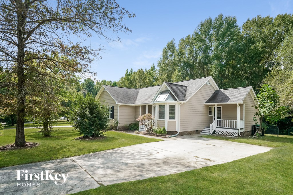 a cream colored house with a driveway and trees