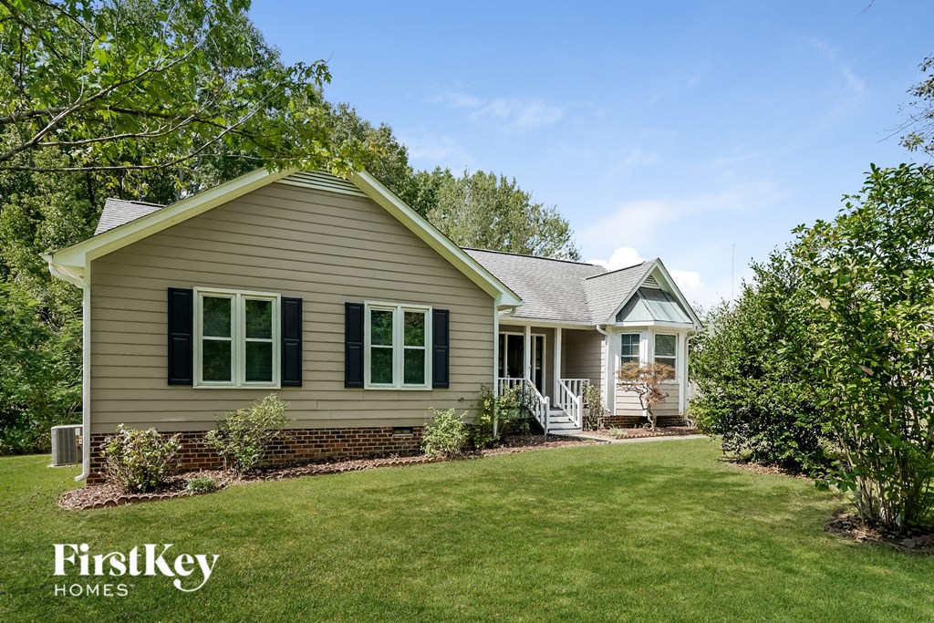 a home with green shutters and a green lawn and trees