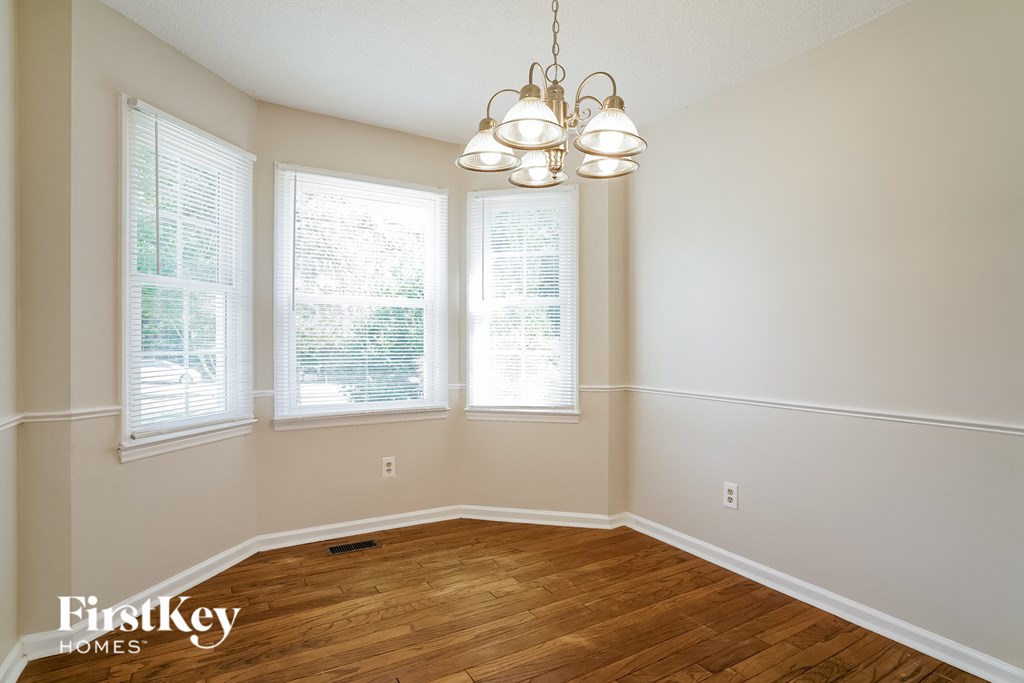 an empty dining room with a wooden floor and a chandelier