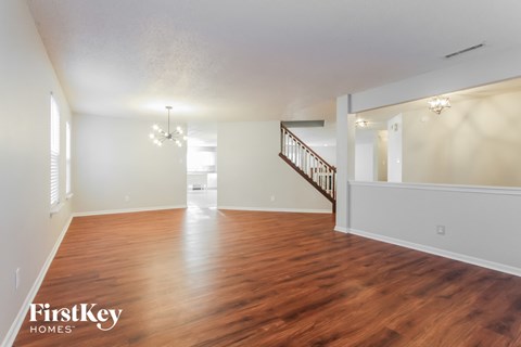 A spacious room with wooden floors and a staircase.