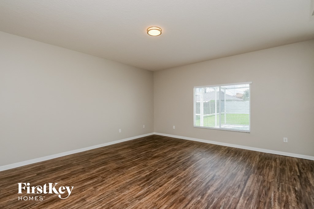 the spacious living room with hardwood flooring and a window