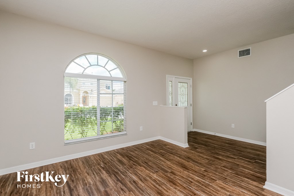 the living room of a home with a large window and wooden floors