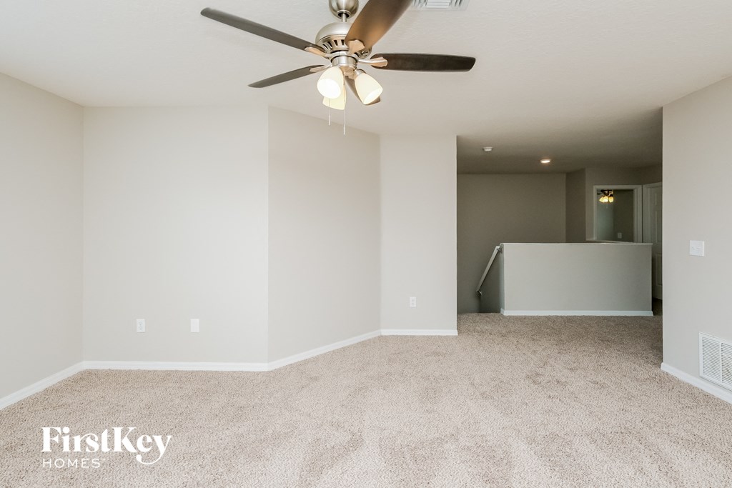 a spacious living room with carpet and a ceiling fan