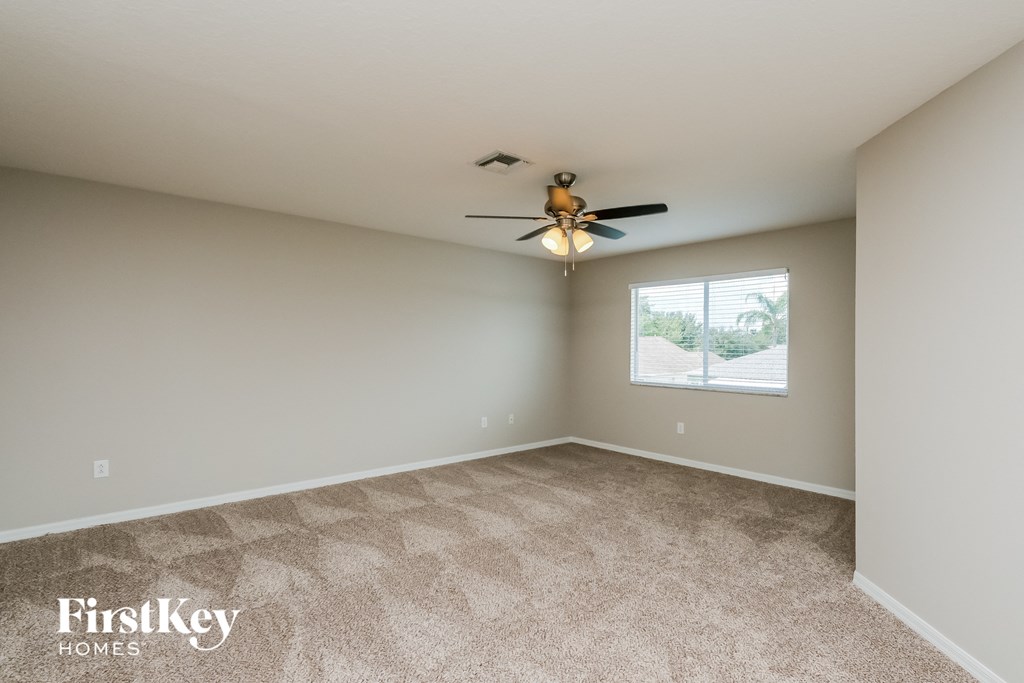 an empty living room with a ceiling fan and a window