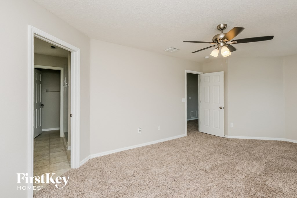 an empty living room with a ceiling fan and a hallway