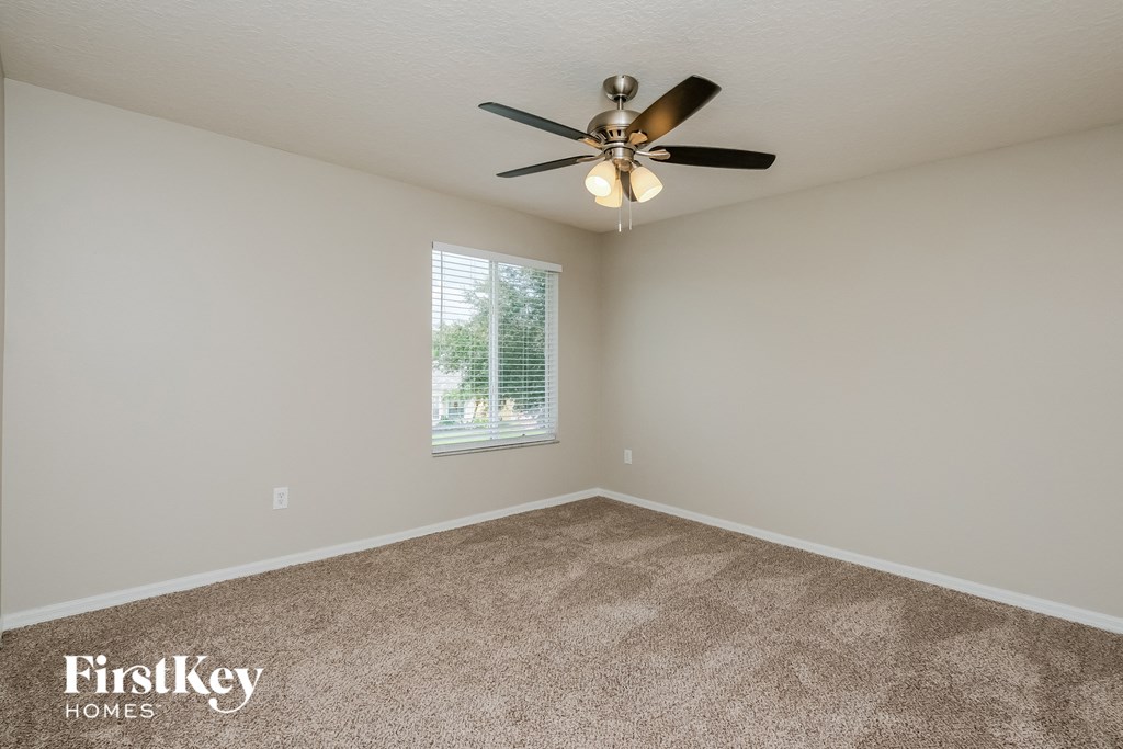 an empty room with a ceiling fan and a window