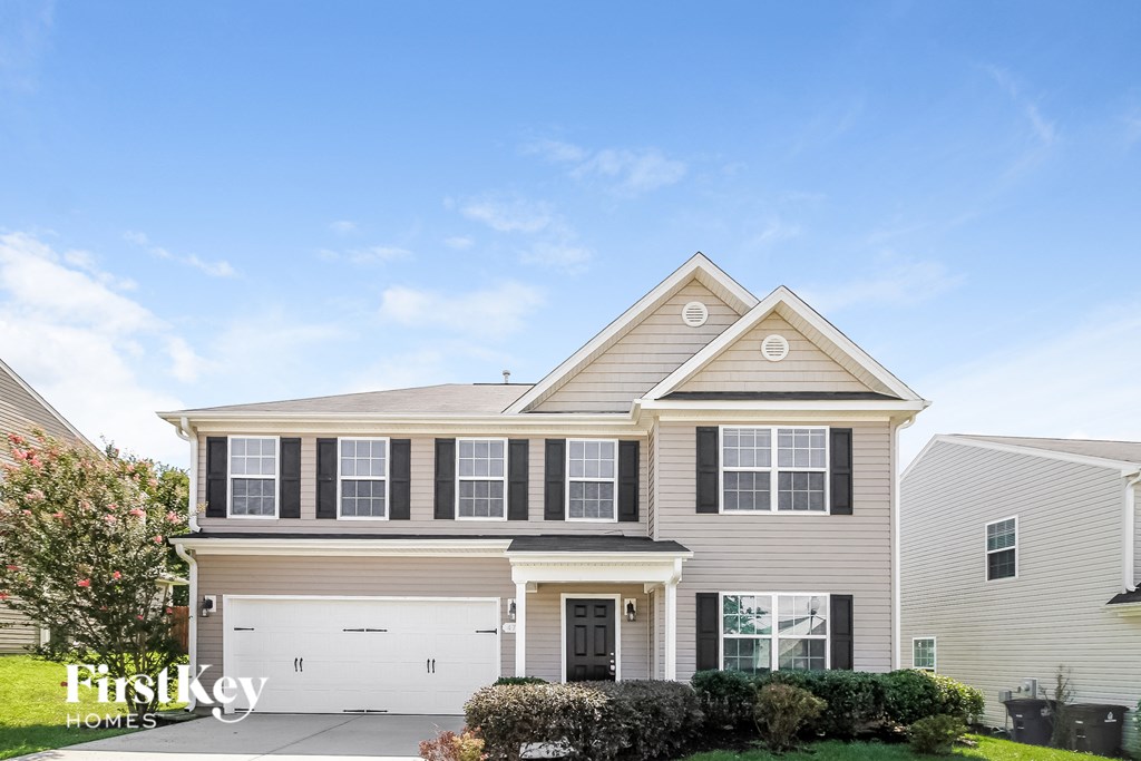 A house with a garage and a driveway in front of it.