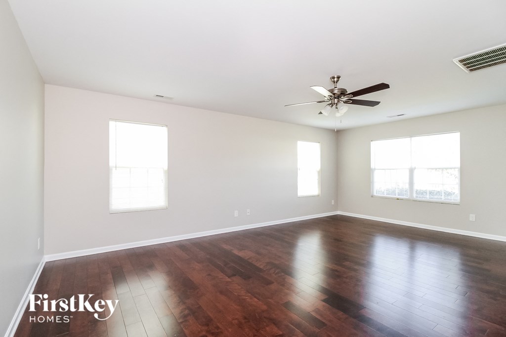 A spacious room with wooden floors and a ceiling fan.