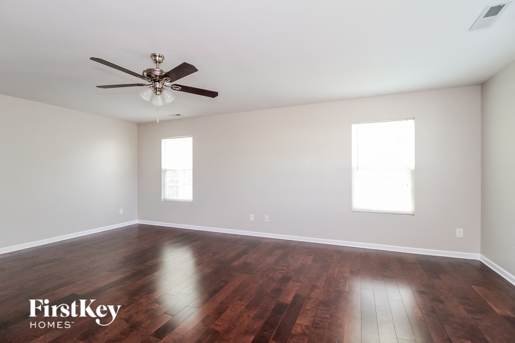 A room with a ceiling fan and two windows.