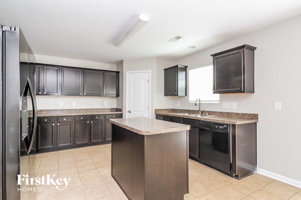 A kitchen with a refrigerator, cabinets, and a countertop.