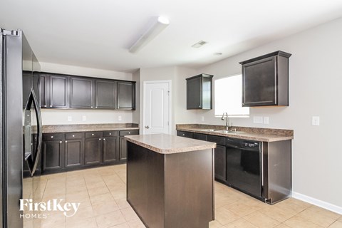 A kitchen with a refrigerator, cabinets, and a countertop.