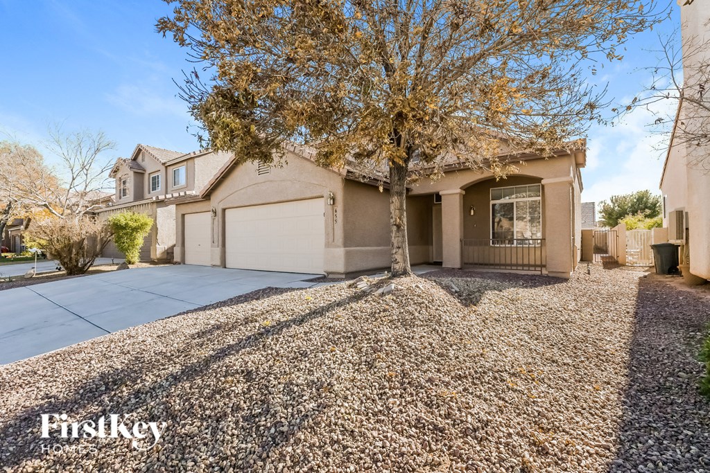 A house with a gravel driveway and a tree in front.