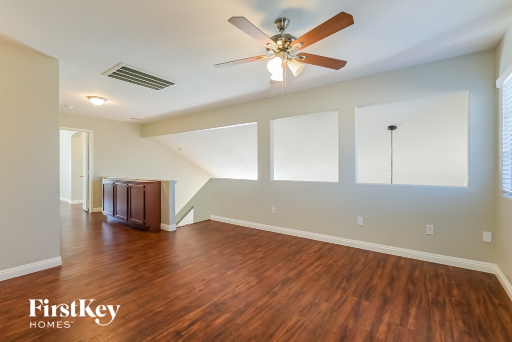 A spacious room with a wood floor and a ceiling fan.