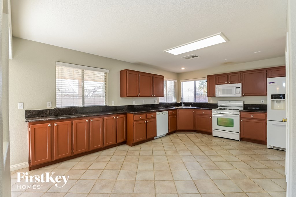 A kitchen with brown cabinets and white appliances.