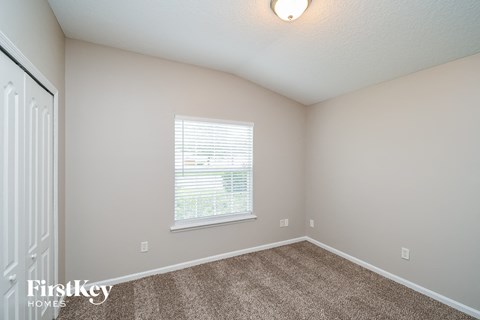 a spacious bedroom with carpet and a window