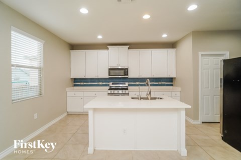 A kitchen with white cabinets and a black refrigerator.
