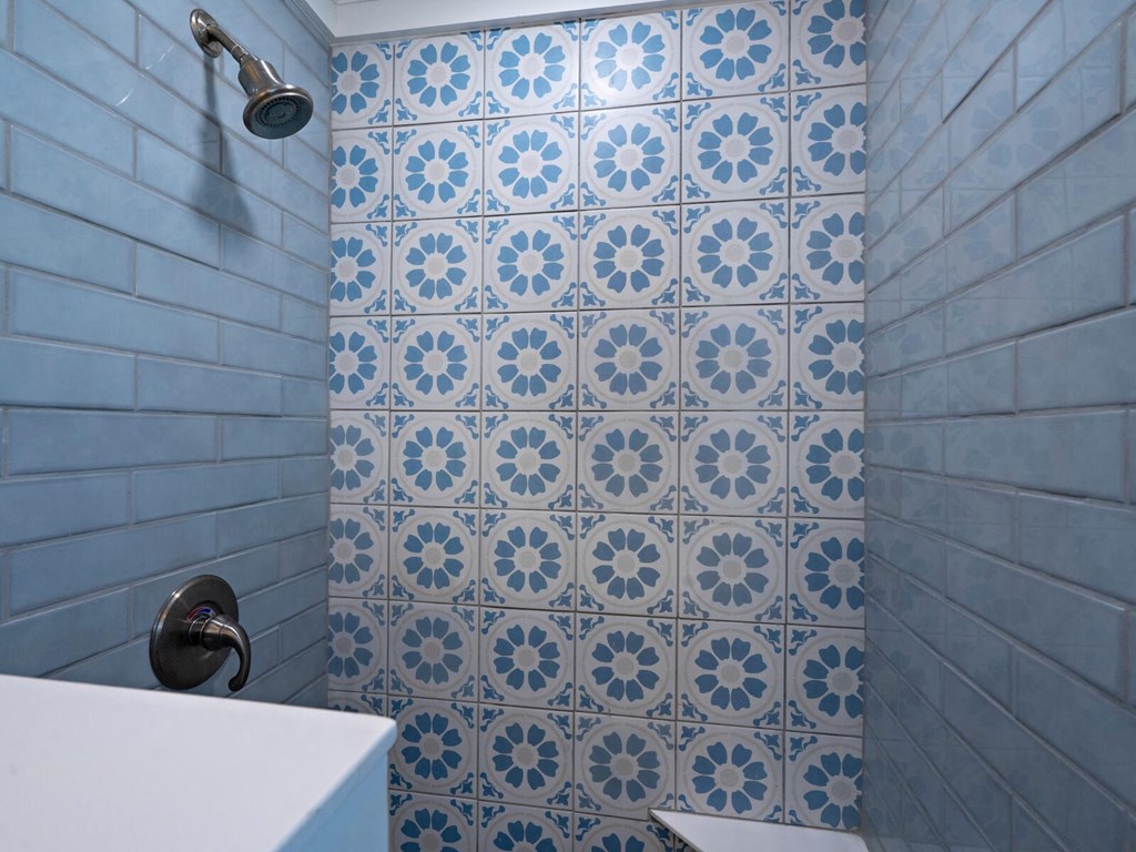 a bathroom with blue and white tiled walls and a shower