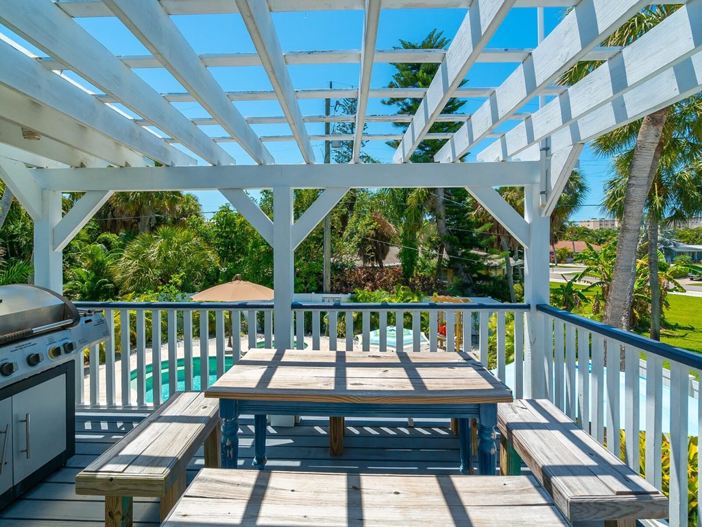 a picnic table on the deck of a house with a grill