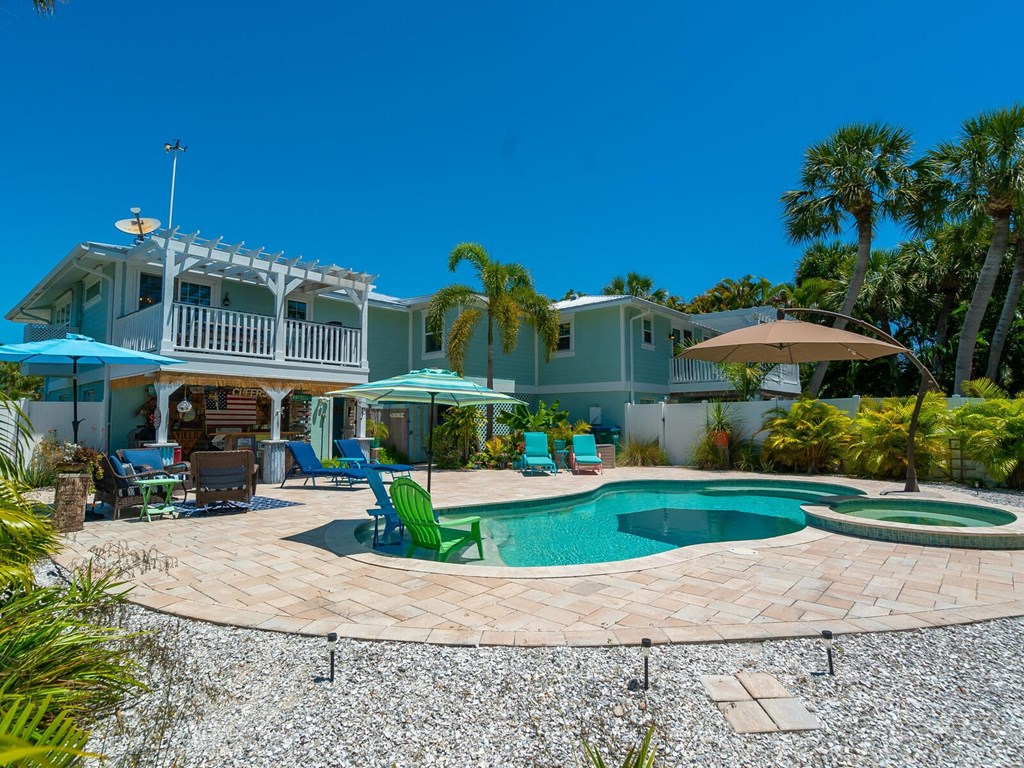 a house with a swimming pool and a patio with chairs and umbrellas