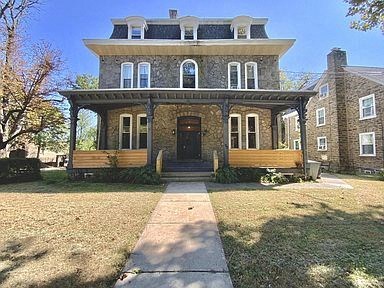a brick house with a porch and a sidewalk