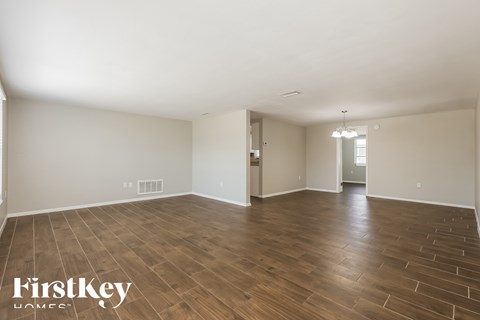 A spacious room with wooden flooring and white walls, branded with "FirstKey Homes".
