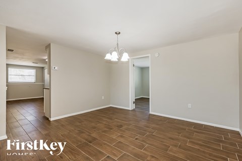 A spacious room with wooden flooring and a chandelier hanging from the ceiling.