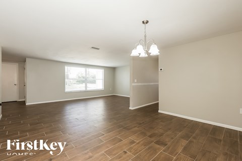 A spacious room with wooden flooring and a chandelier hanging from the ceiling.