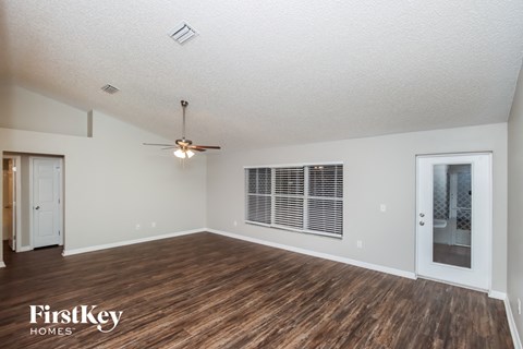 A spacious room with wooden flooring and a ceiling fan.