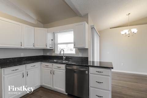 A kitchen with white cabinets and a black countertop.