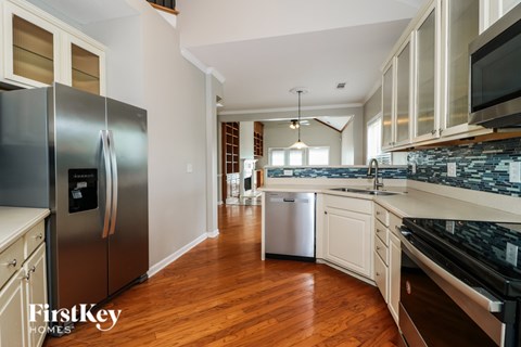 A kitchen with a stainless steel refrigerator and wooden floors.