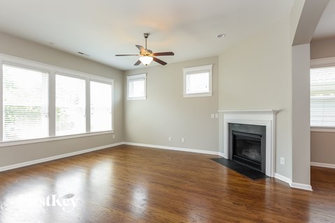 A spacious living room with a fireplace and a ceiling fan.
